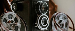 Vintage filmcamera met een grote lens en filmspoelen.