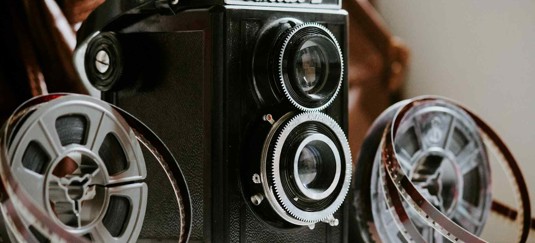 Vintage filmcamera met een grote lens en filmspoelen.