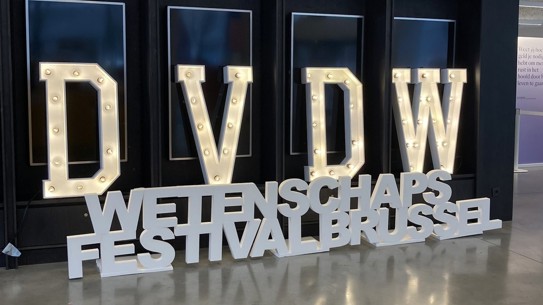 Verlichte letters DVDW en WETENSCHAPS FESTIVAL BRUSSEL in een eigentijdse expositieruimte.