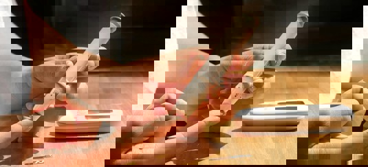 Een persoon die aan tafel zit en suikerspiegel meet