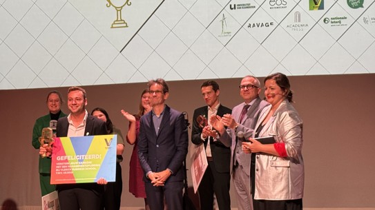 Photo of the winner of the Flemish PhD Cup holding his trophy and check.