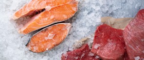 Freshly sliced salmon and pieces of red meat resting on a bed of ice.